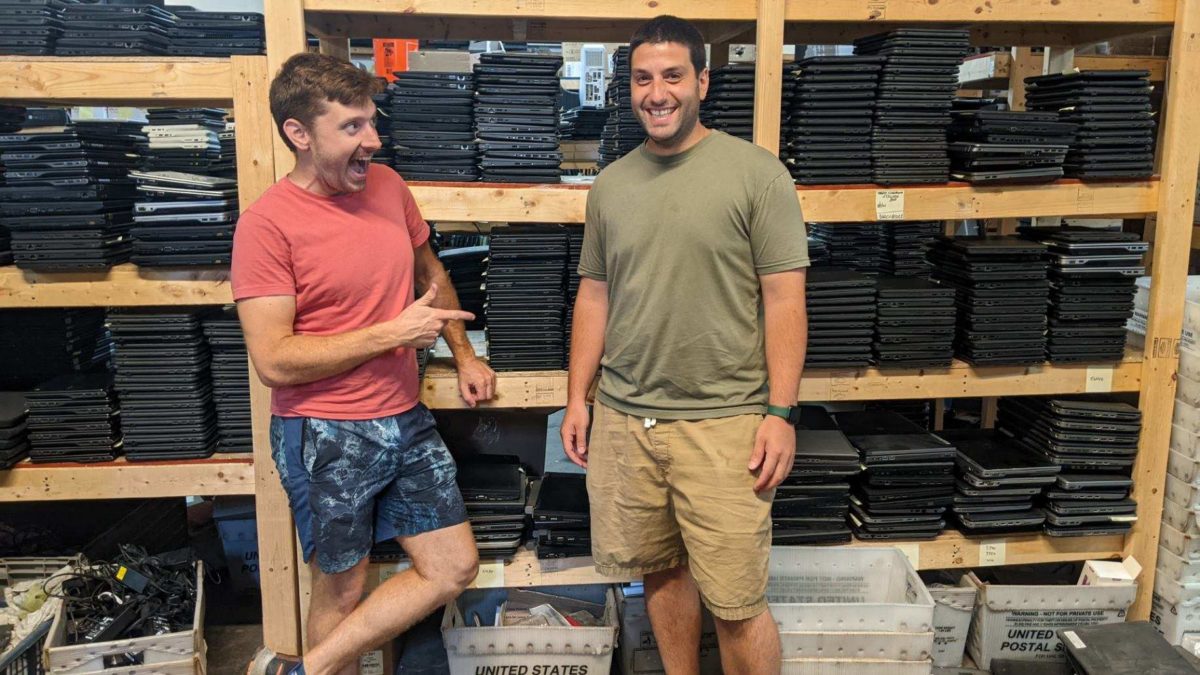 The owners of JCS Computer Store standing in front of a shelf holding their products.