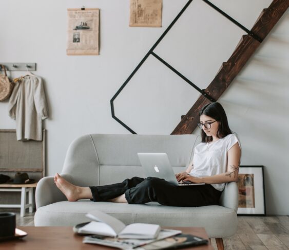 Woman working on a laptop from her couch.